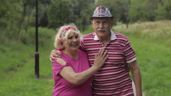 Senior Caucasian Couple Walking in Park Embracing. Elderly Man Walks with Woman. Husband, Wife