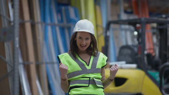 Cheerful Woman Making Victory Gesture Looking at Camera Smiling and Walking Away in Industrial