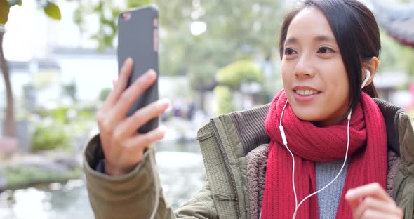 Woman taking live stream on cellphone in chinese garden