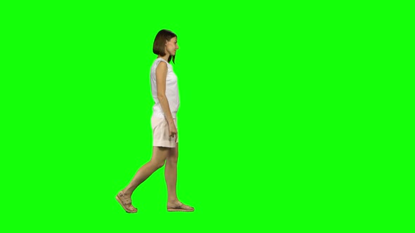 Young Woman with Brown Hair and a Smooth Haircut Is Calmly Walking on Green Screen. Chroma Key, Shot