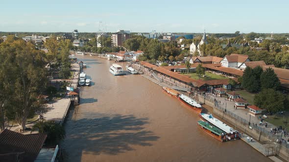 Aerial view of Tigre river with a catamaran sailing and boats docked at sides. Dolly in