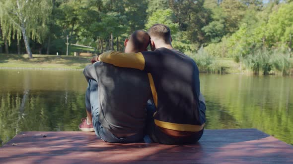 Rear View of Gay Couple Embracing on Jetty By Lake