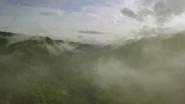 Aerial view flying above lush green tropical rain forest mountain with rain cloud cover during the r