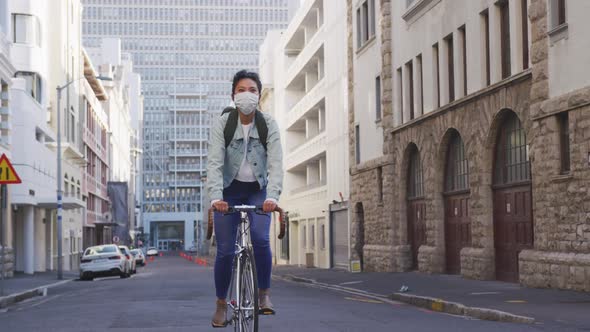 Woman riding on her bike while wearing medical coronavirus mask