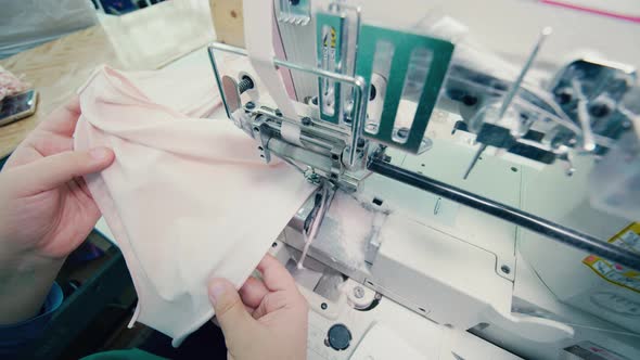 A Worker Is Sewing and Cutting Pieces of Fabric with a Sewing Machine