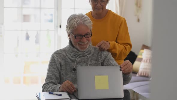 Couple of two old and mature people at home using tablet together in sofa. Senior use laptop