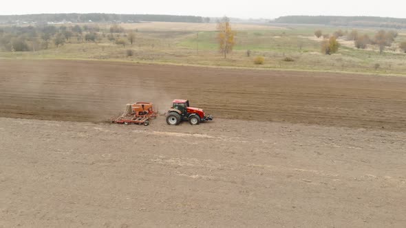 Farmer on an Energy-saturated Tractor with a Sowing Unit Sows Seeds of Winter Crops on a Field