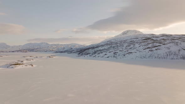 Drone tracks eagle in flight over snowy frozen lake; Ringvassoya, Norway