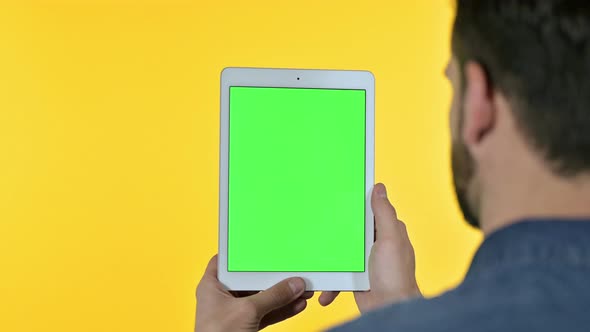 Man Looking at Tablet with Chroma Screen, Yellow Background