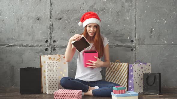 Happy red-haired girl opens a box with a gift