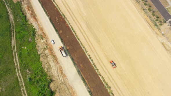 Dumper truck with sand is going, passing over highway construction side. Aerial View
