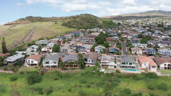 Reverse pullback aerial shot of houses on a mountainside in Kapolei on the island of O'ahu, Hawaii.