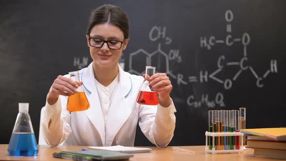 Chemistry Teacher Comparing Liquids in Flasks and Showing to Camera, Discovery