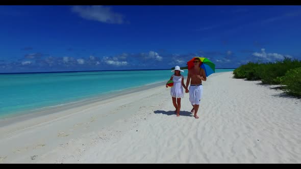 Two people engaged on tranquil coastline beach break by turquoise ocean and white sandy background o