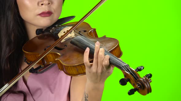 Girl Fingering the Strings Playing on a Brown Violin. Close Up. Green Screen