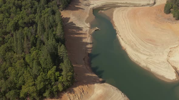 Aerial view of Shasta Lake rotating around trees looking at the water in Northern California low wat