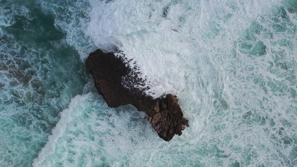 Rugged ocean rock battered by waves in Praia Do Tonel, near Cape Sagres Portugal, Aerial lowering ro