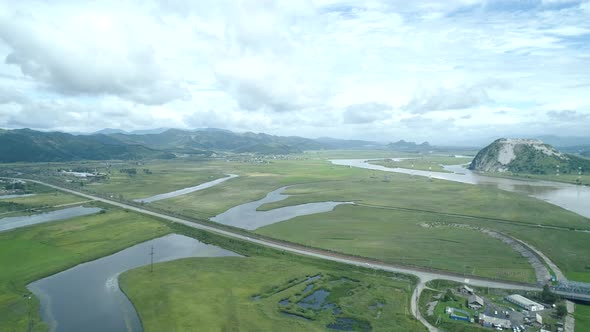 Aerial Drone View of Beautiful Natural Scenery of Road in Green Meadow with River Mountains in