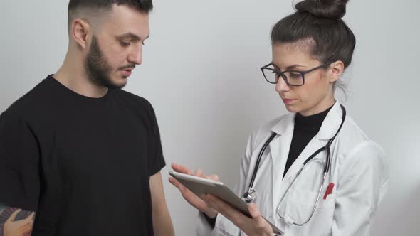 Young Female Doctor Noting Down Patient Symptoms, Explaining the Man the Danger of Coronavirus