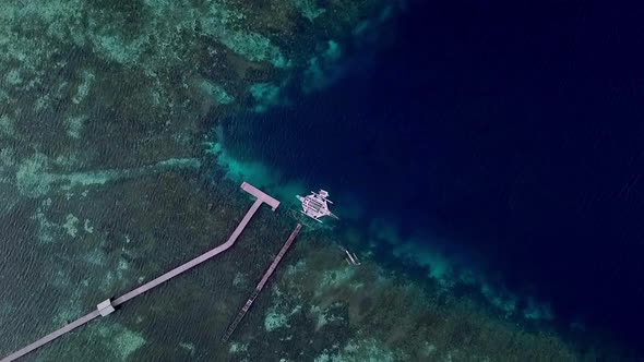 Jukung boat in Raja Ampat islands Indonesia stationed on a pier while another smaller boat navigates