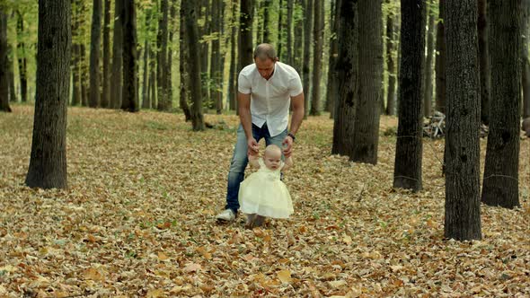 Father and His Baby Make First Step in Autumn Park