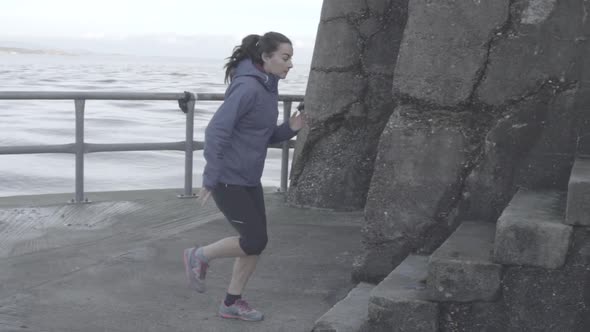 A young woman running on a breakwall.