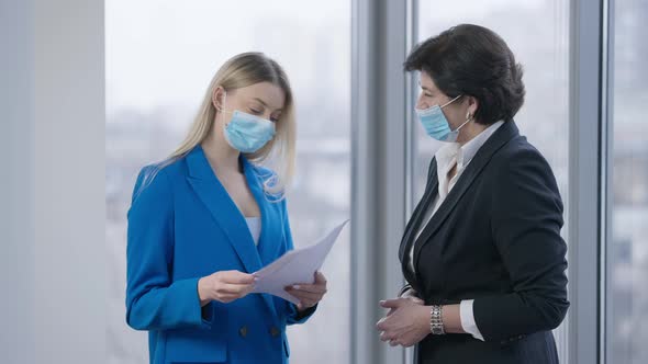 Middle Aged and Young Women in Covid Face Masks Analyzing Documents Talking and Shaking Head Yes in