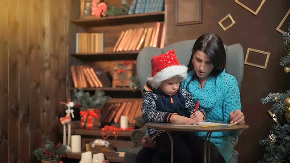 Mother and Little Son Writing Letter to Santa Claus