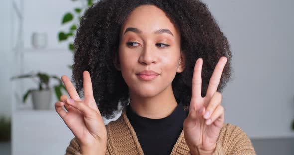 Closeup Front Portrait of African American Positive Teen Girl Posing Indoor Shows Two Fingers v