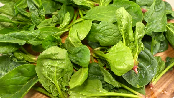 Spinach leaves on a wooden cutting board.