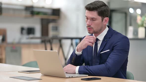 Pensive Businessman Thinking and Working on Laptop in Office 