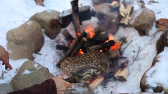 Native Man Stokes Camp Fire in Winter