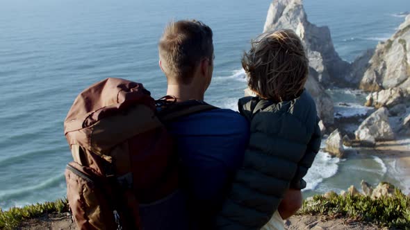 Father with Camping Backpack Holding Daughter Kid in Arms