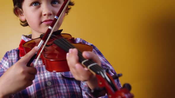 Schoolboy playing violin in classroom at school