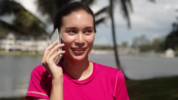 Modern Active Female in Sportswear Talking on Smartphone and Smiling While Standing