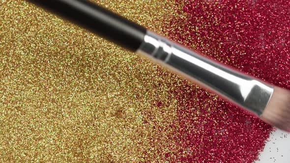Smearing Red and Gold Glitter on a White Background Gloss Powder Closeup