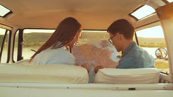 Friends Using Map Traveling In Car In Summer. Handsome Man And Beautiful Woman