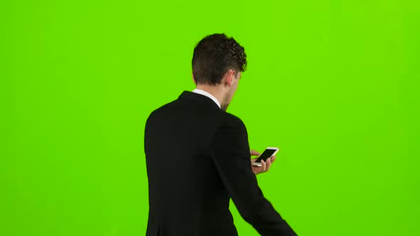 Man Is a Telephone Rings To Him and He Talks. Green Screen. Back View