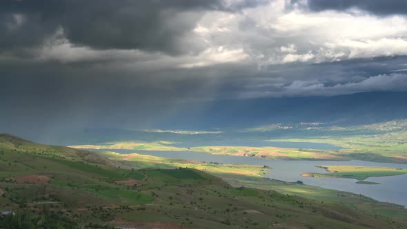 Storm Clouds and Rain Approaching to Lake Geography Surrounded by Hilly Meadows