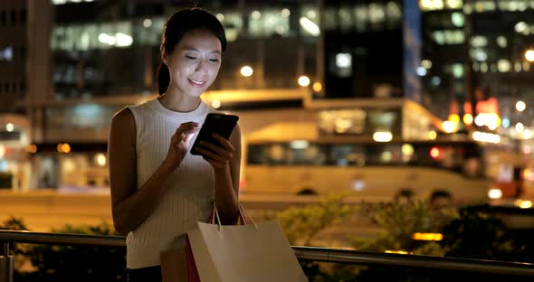 Woman using mobile phone in Hong Kong at night 