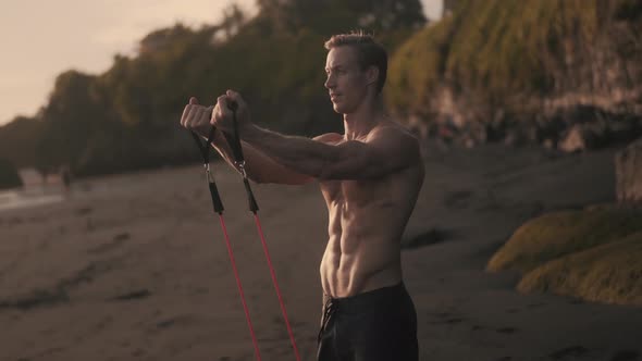 Young Athletic Caucsian Man Lift Ups His Arms with Resistance Band