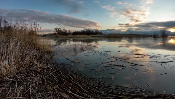 Cloudsing swiftly across the sky and reflecting off the surface of a lake while the sun rises in thi