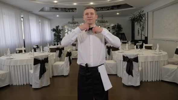 Portrait of a Waiter in a Restaurant Before Work He Straightens His Bow Tie