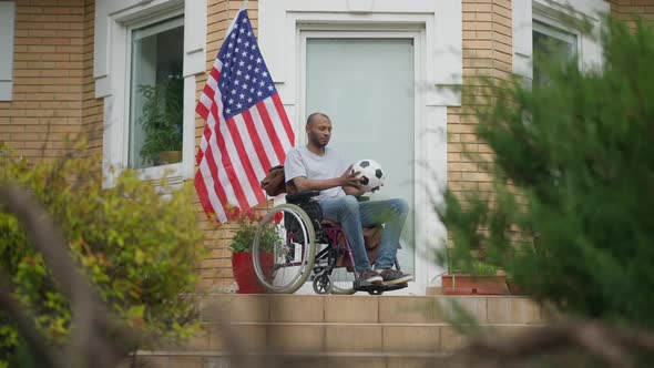 Frustrated African American Disabled Man Sitting in Wheelchair Holding Soccer Ball