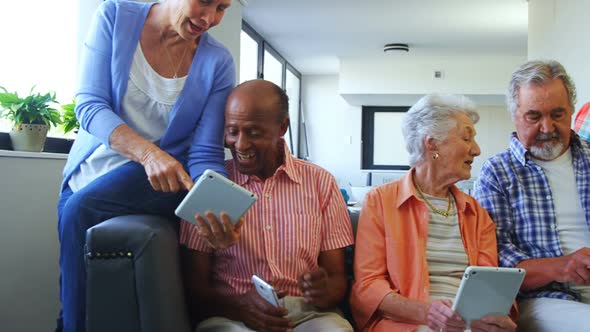 Happy senior friends using digital tablet on sofa