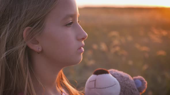 Young Girl with Teddy Bear in the Field and Look Sunset.