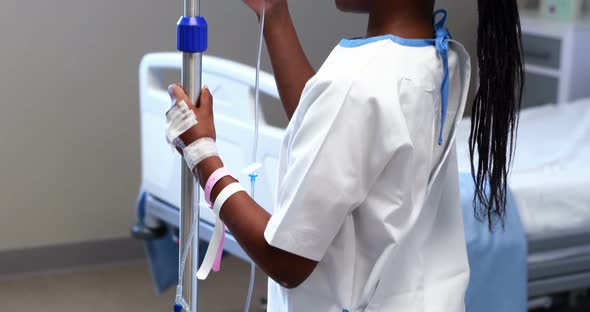 Portrait of sick girl holding iv drip stand