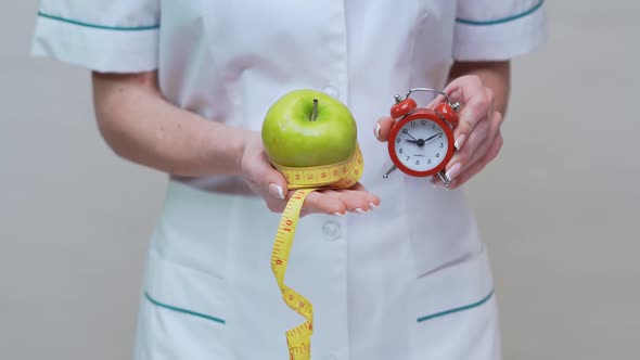 Nutritionist Doctor Healthy Lifestyle Concept - Holding Green Apple, Alarm Clock and Measuring Tape