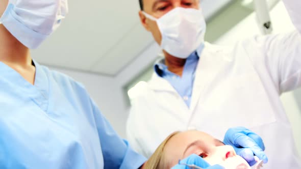 Dentist and nurse examining a young patient with tools