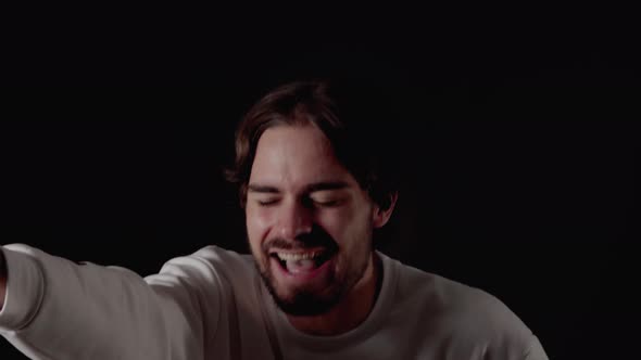 Trendy Young Man laughing at camera, pointing gesture, close, black background